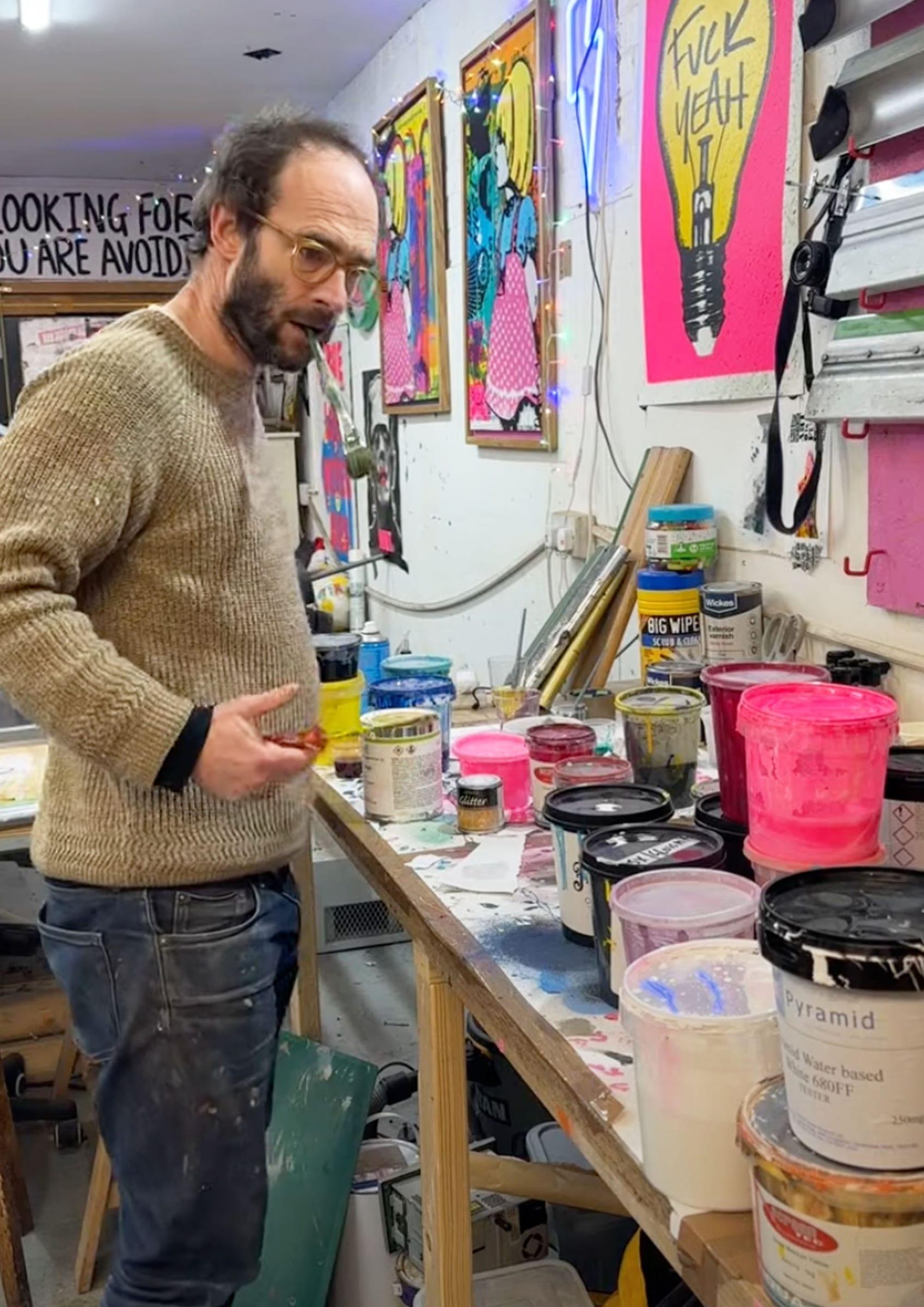 Oli at the ink station surrounded by paint tins