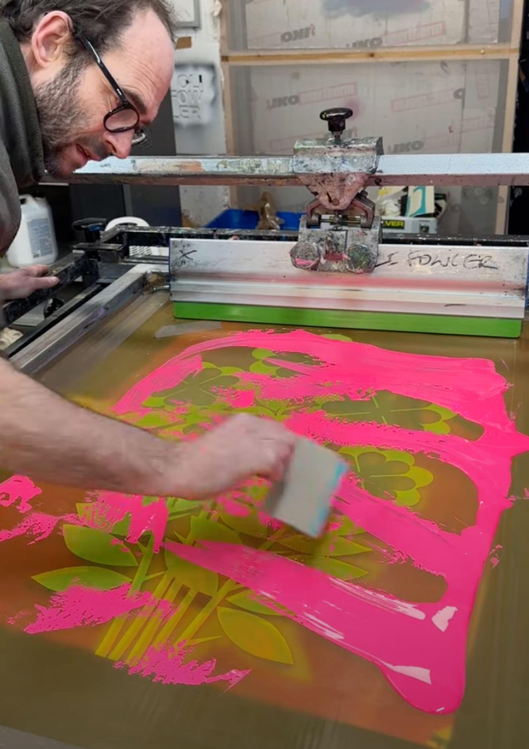 Pulling the squeegee through pink ink across the screen